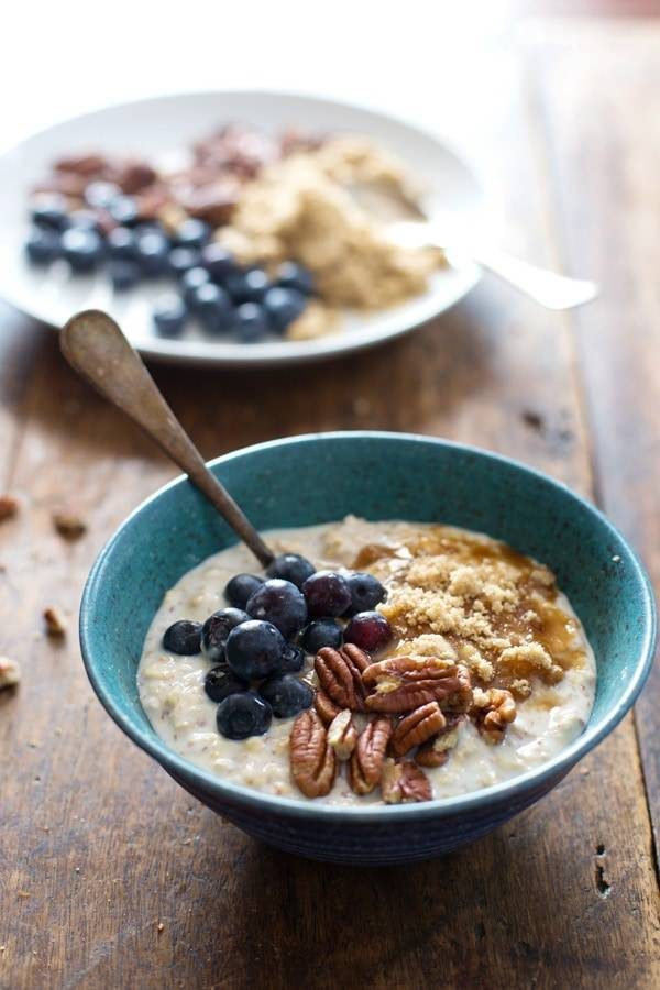 Overnight oats with flax, blueberry, and vanilla yogurt in blue bowls with a spoon.