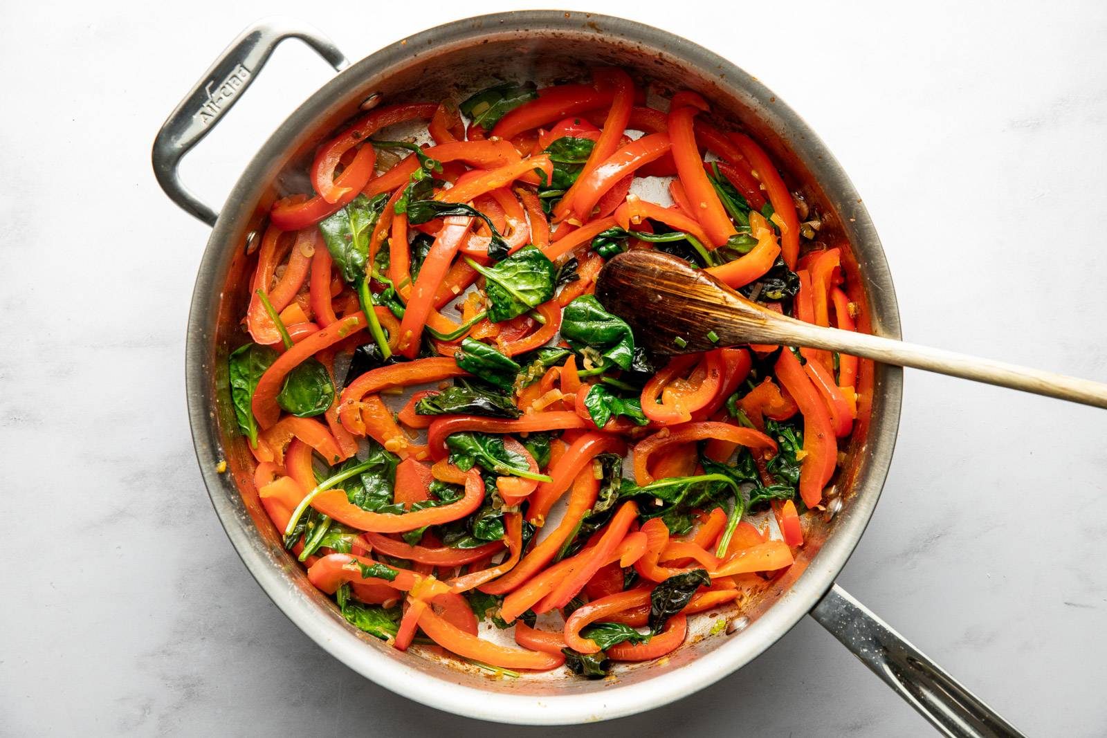 Peppers and spinach sautéed in a pan.
