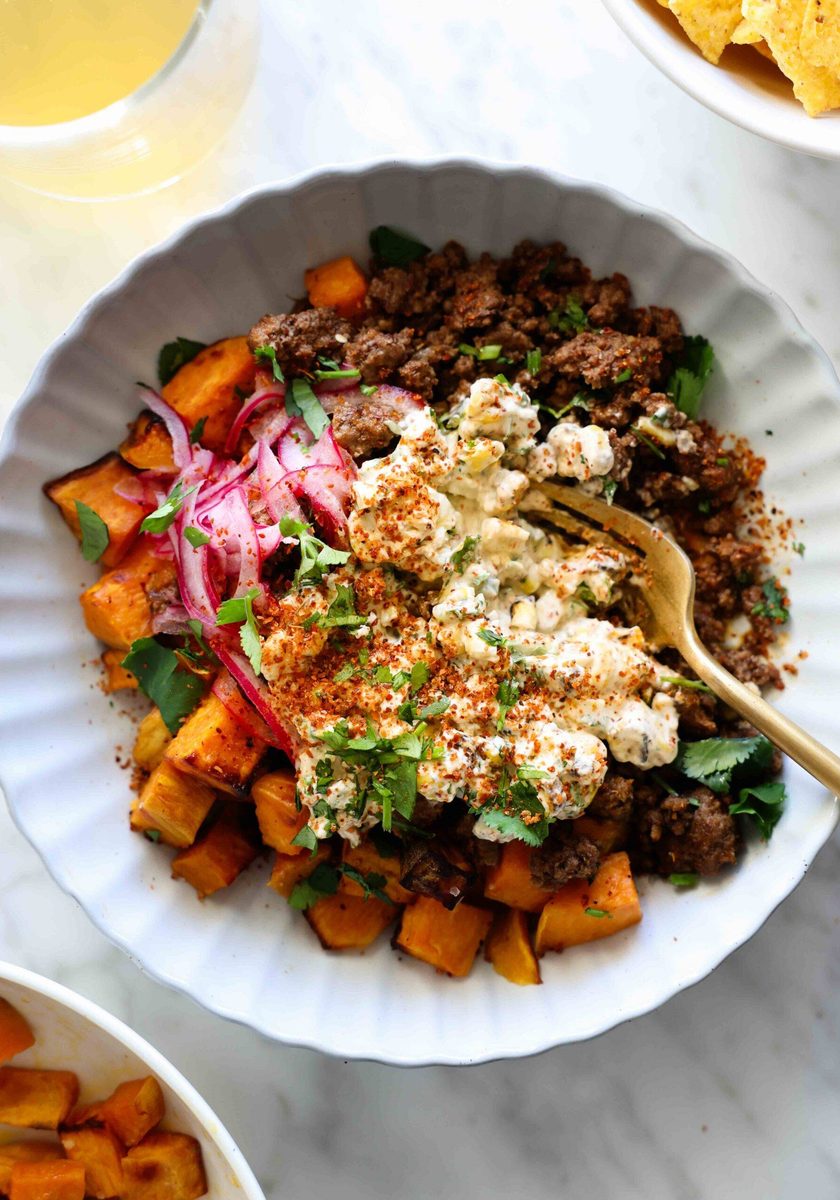 Beef and sweet potato in a bowl with street corn.