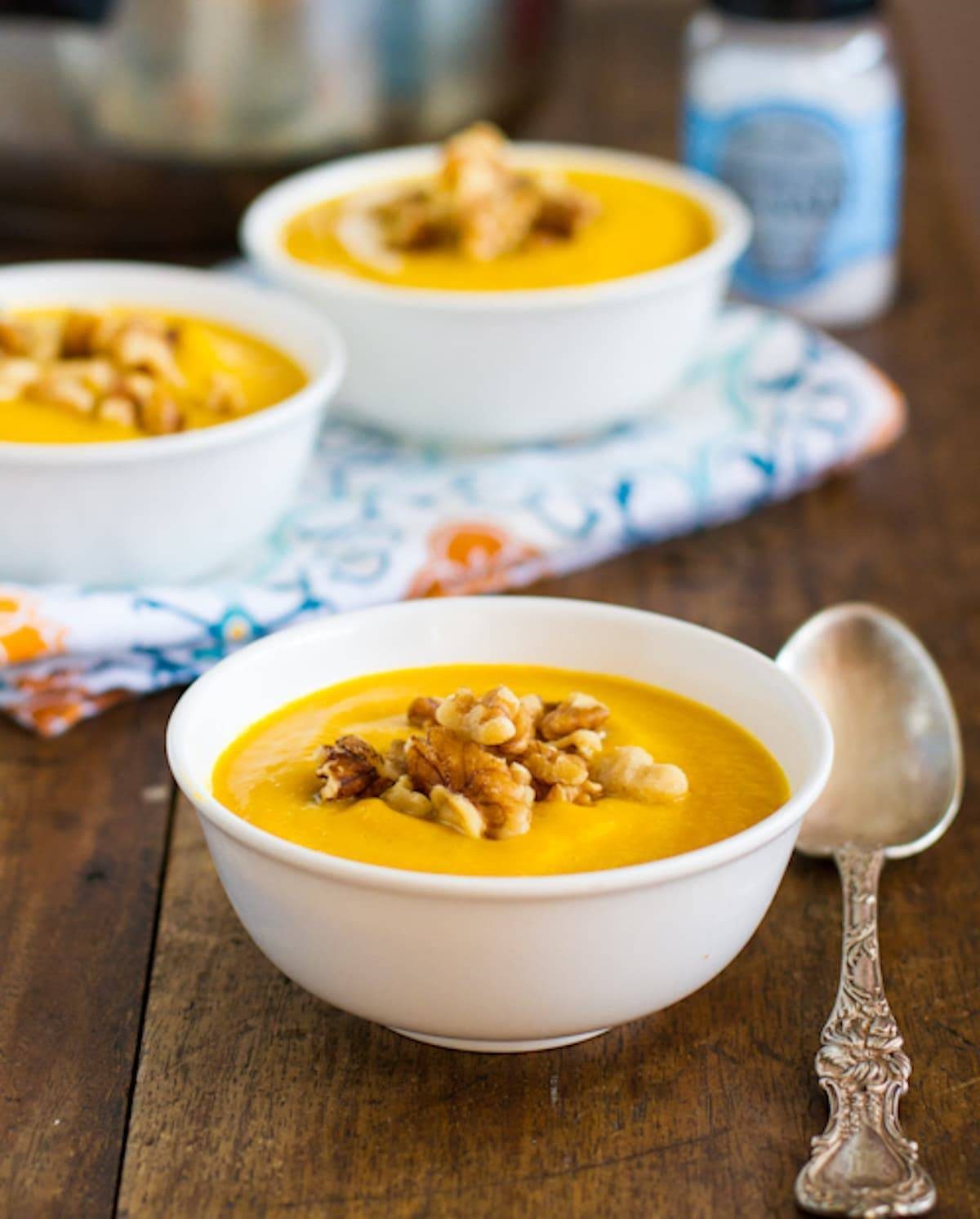 Three bowls of creamy squash soup with walnuts.