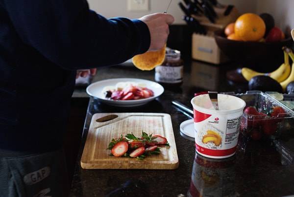Strawberries on a cutting board in a kitchen.