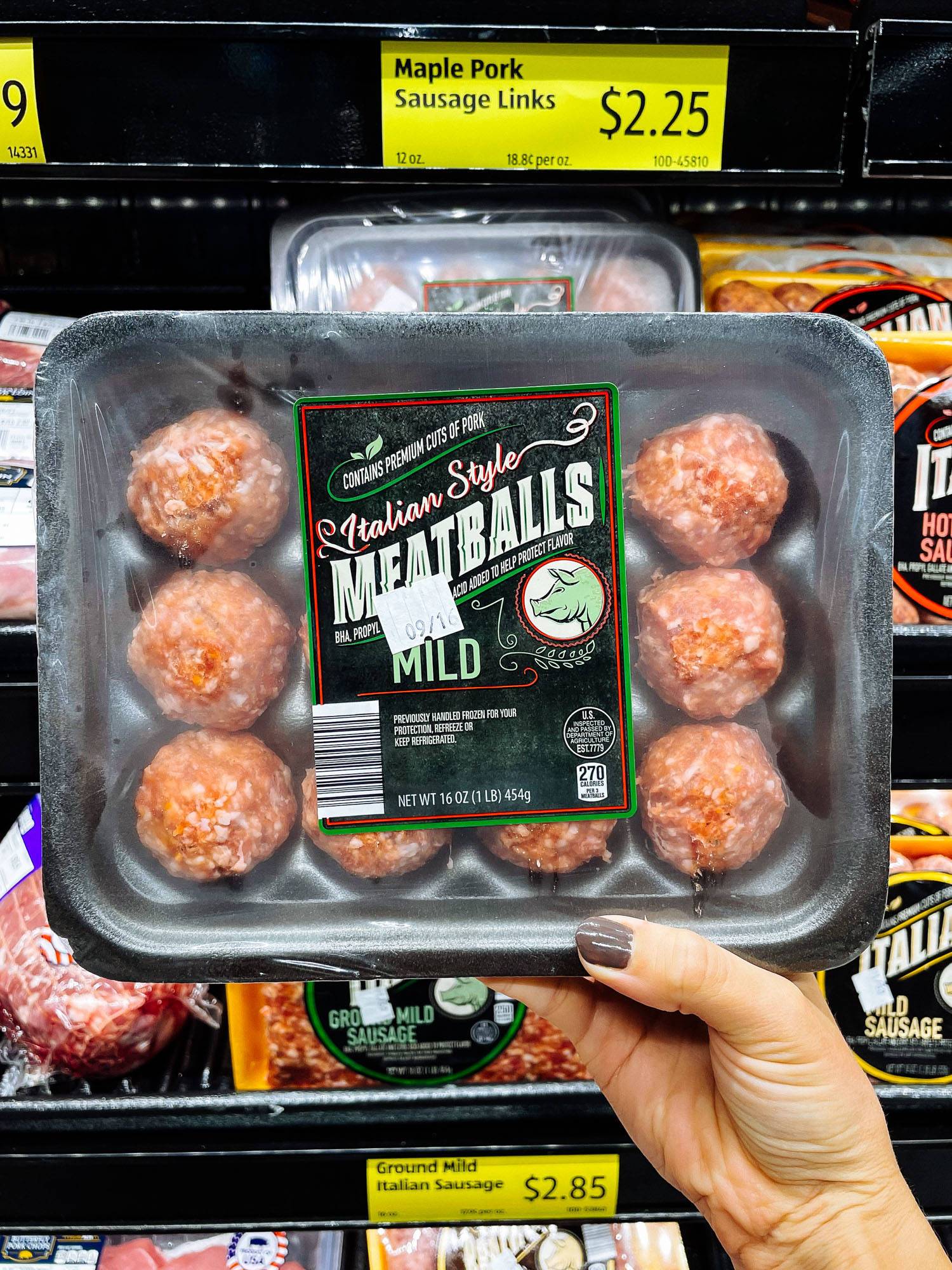White hand holding Italian-style meatballs from ALDI.