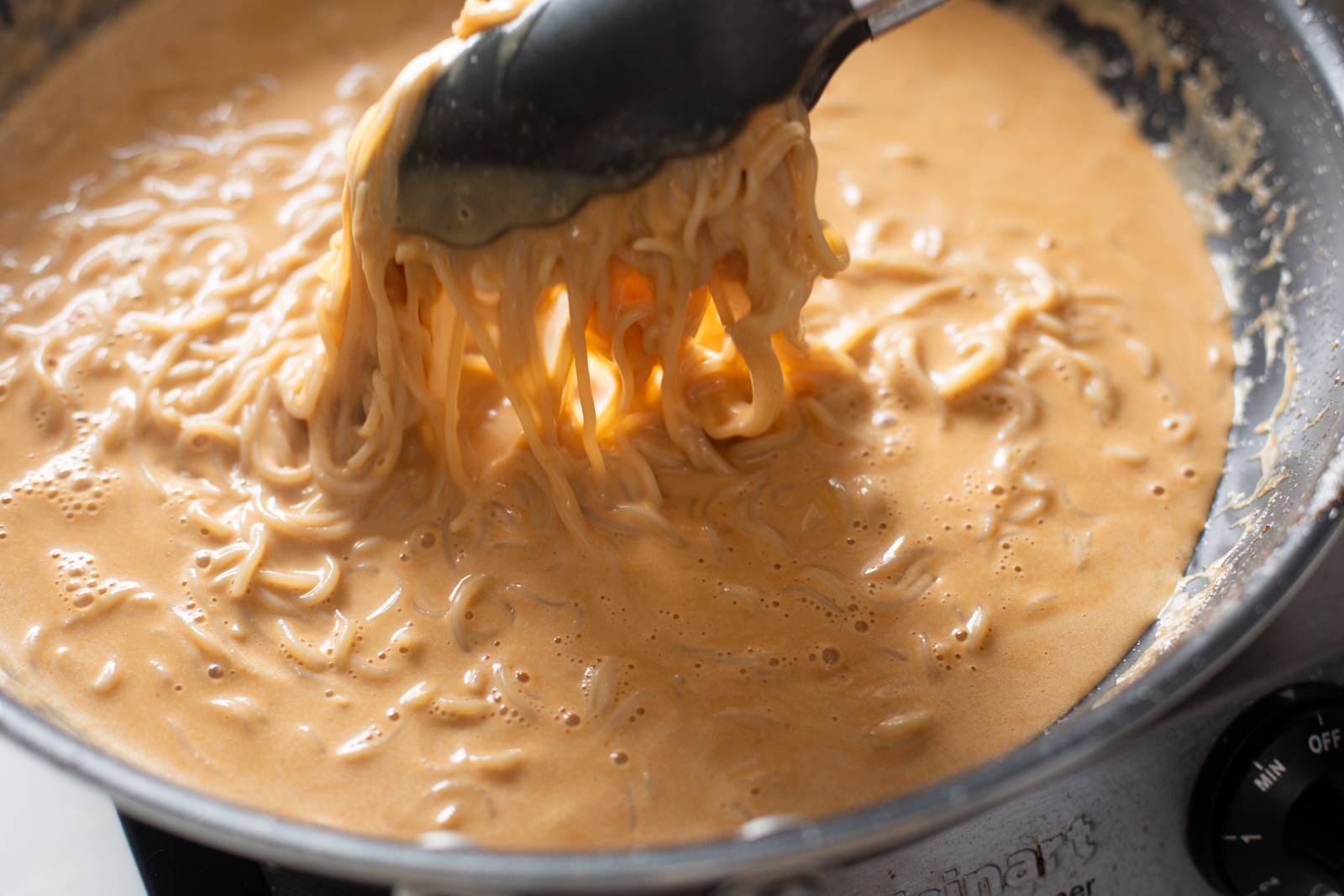 Adding noodles to a skillet.