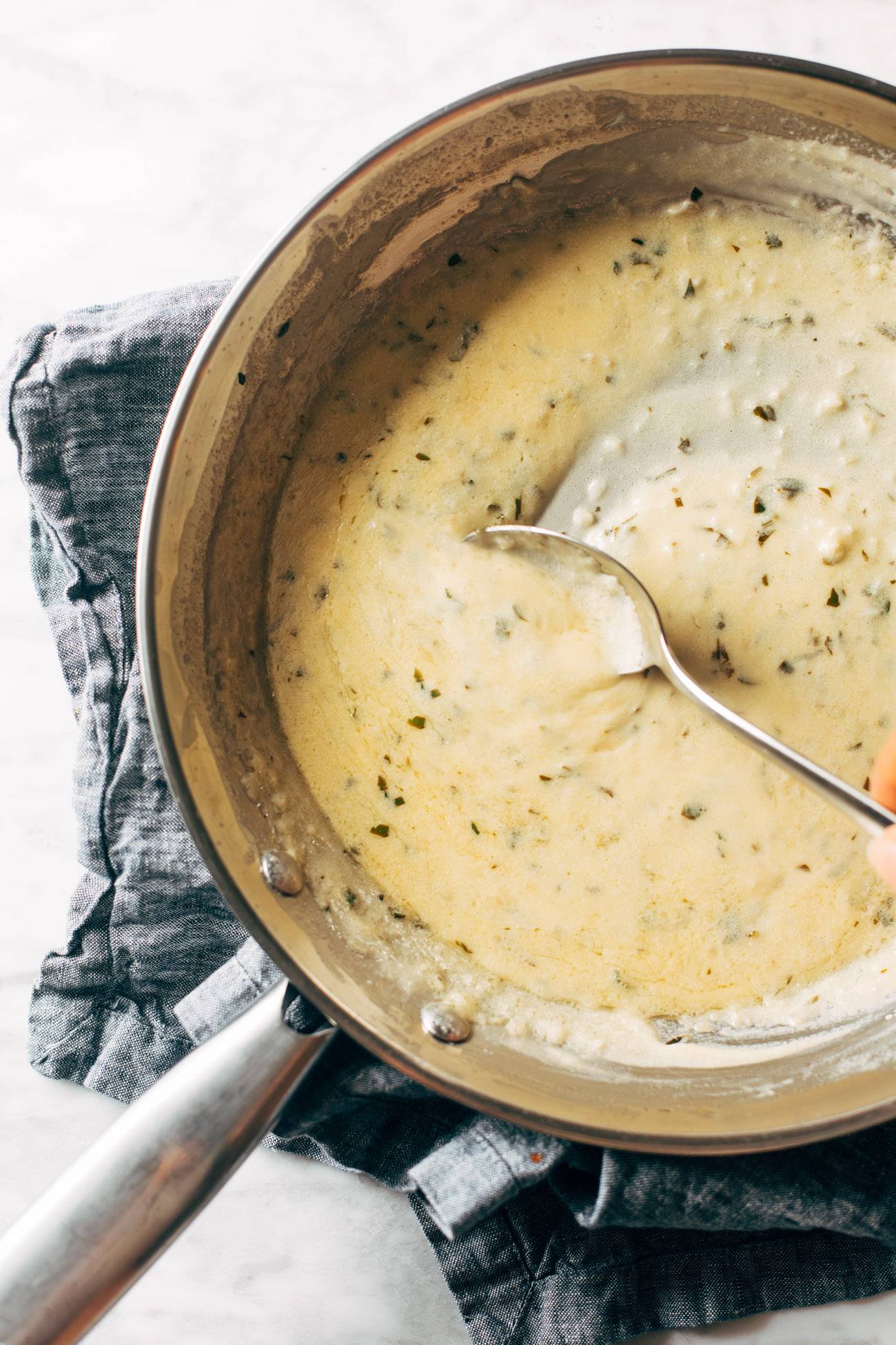 Amazing lemon sauce in a pan being stirred with a metal spoon.
