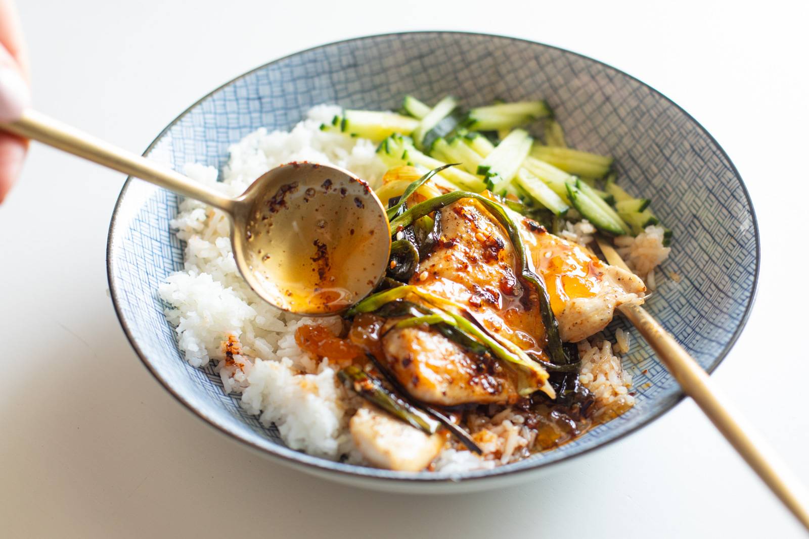 Apricot chicken in a bowl with rice and cucumber.