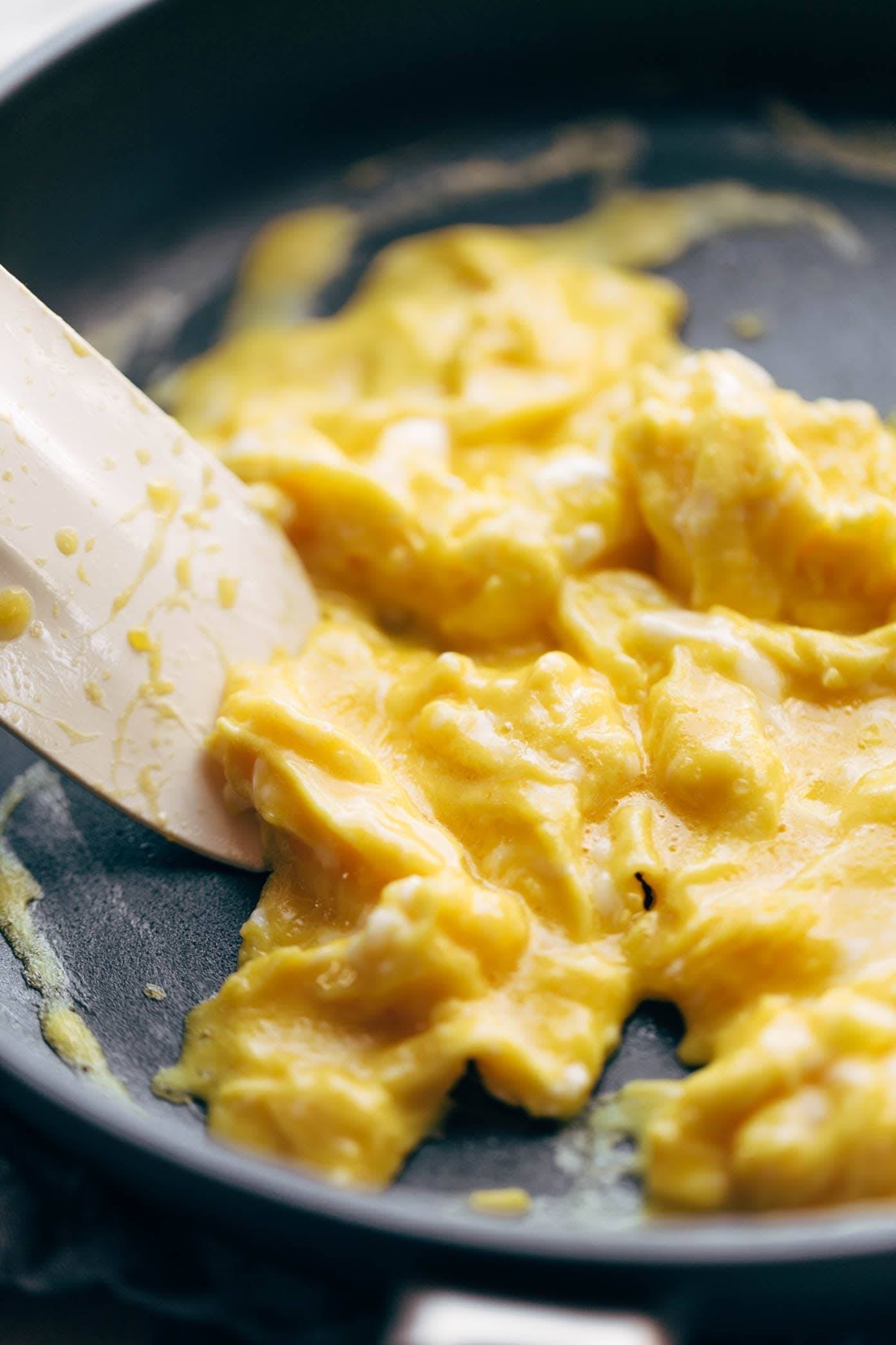 Soft scrambled eggs in a pan with a spatula.